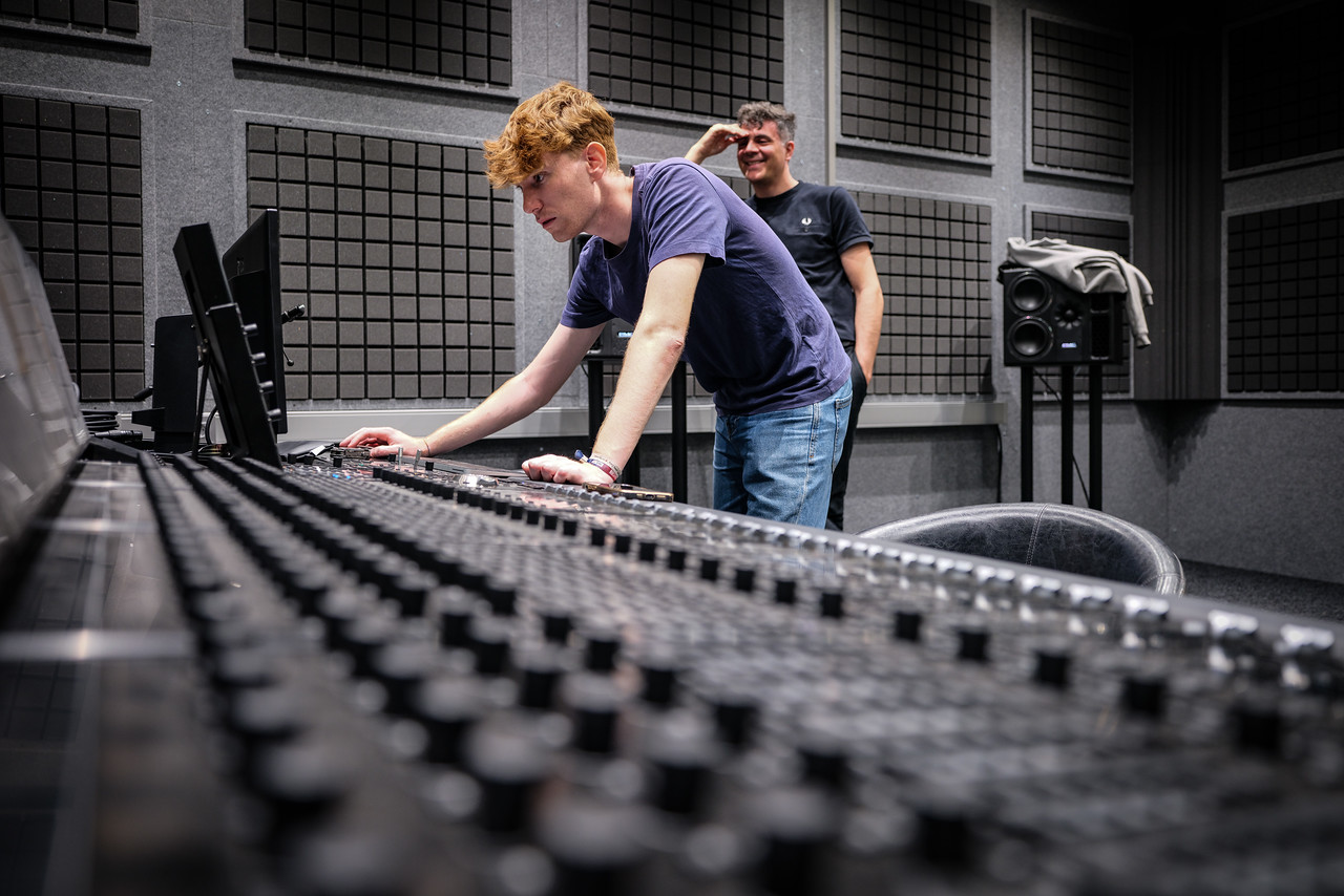Dos personas trabajando en la mesa de mezclas de un estudio de sonido